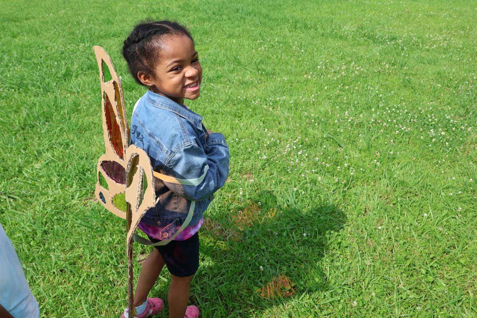 Young learner wearing handmade cardboard butterfly wings outdoors